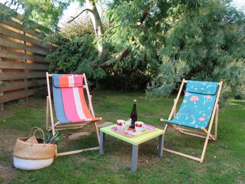 2 chaises longues et une table avec une bouteille de vin. dans l'établissement Chalet Le Chalet - A, à Cancale