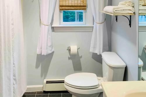 La salle de bains blanche est pourvue de toilettes et d'une fenêtre. dans l'établissement The Gould Cape House, à Eastham