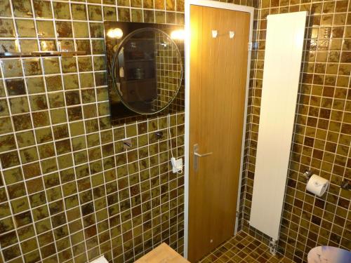a bathroom with a mirror and a brown tiled wall at Studio Jeanne D'Arc Apt- E-36 by Interhome in Crans-Montana