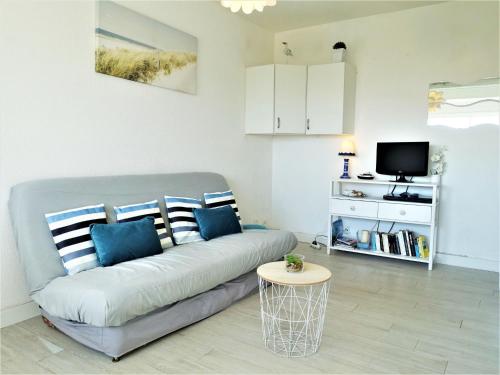ein Wohnzimmer mit einem Sofa und einem TV in der Unterkunft Apartment Les Balcons de la Méditerranée-15 by Interhome in Narbonne-Plage