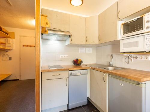une petite cuisine avec des armoires blanches et un évier dans l'établissement Studio Le Bollin - Val Claret-3 by Interhome, à Tignes