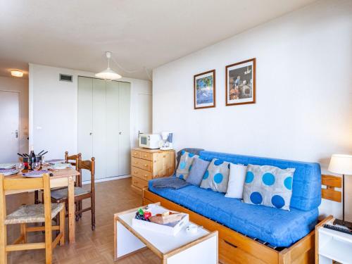 uma sala de estar com um sofá azul e uma mesa em Apartment Lunik Orion-18 by Interhome em Le Corbier