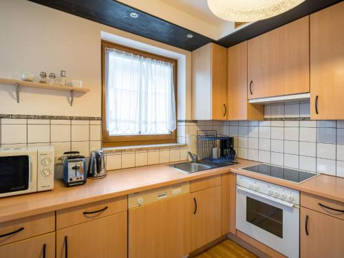 een keuken met houten kasten, een magnetron en een wastafel bij Apartment Haus Kitzsteinhorn by Interhome in Zell am See