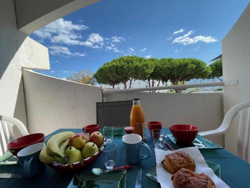 a table with a bowl of fruit and a basket of bread at Apartment Le Viking by Interhome in La Grande Motte