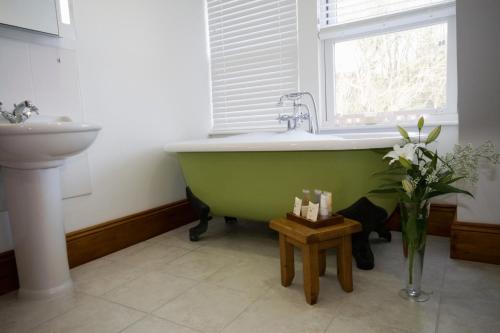 a green bath tub in a bathroom with a window at Stocks Hotel in Sark