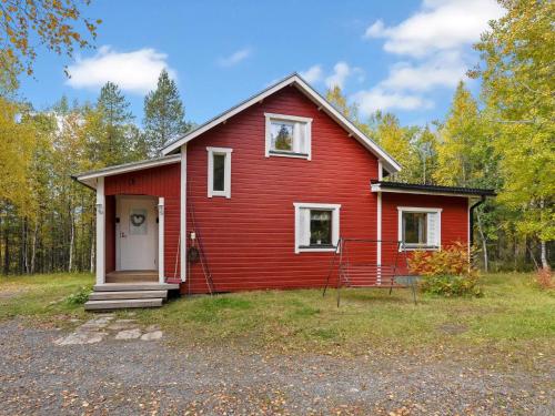 a red house with a white door in the yard at Holiday Home Vuorimäki by Interhome in Ruka