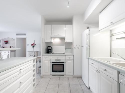 une cuisine blanche avec des armoires et des appareils blancs dans l'établissement Apartment Côté Port by Interhome, à Cavalaire-sur-Mer