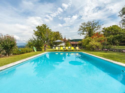 a large blue swimming pool with chairs in a yard at Holiday Home De Ferreira by Interhome in Ponte de Lima
