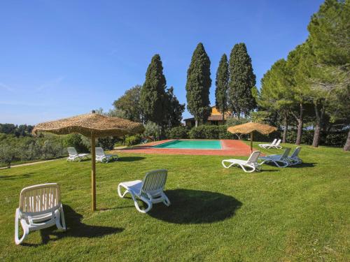 a group of chairs and umbrellas in the grass at Apartment Campiglia-4 by Interhome in Tavarnelle in Val di Pesa