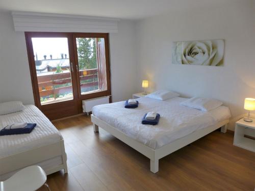 a bedroom with two beds and a large window at Apartment Monte Cristo by Interhome in Crans-Montana