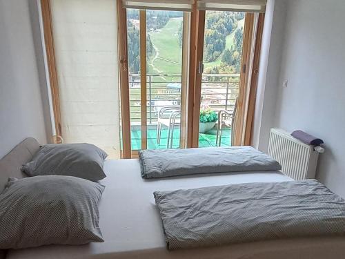 two beds in a room with a large window at APARTMAN "CHARDAK" in Bjelašnica
