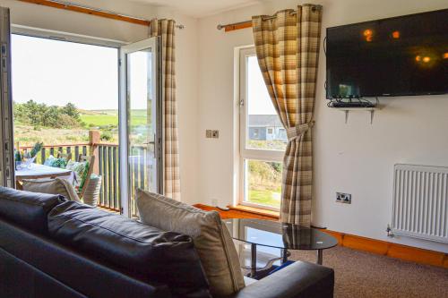 a living room with a couch and a tv at The Fairways in Portpatrick