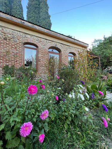 um jardim com flores cor-de-rosa em frente a um edifício de tijolos em Guest House Lali em Signagi