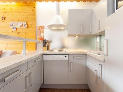 - une cuisine avec des placards blancs et des murs en bois dans l'établissement Apartment Le Bec Rouge - Le Lac-8 by Interhome, à Tignes