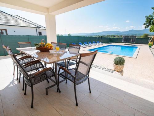 a dining table and chairs on a patio with a pool at Holiday Home Villa Maria by Interhome in Donji Proložac