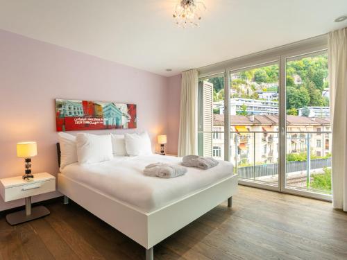 Schlafzimmer mit einem weißen Bett und einem großen Fenster in der Unterkunft Apartment Le Belvédère D2-6 by Interhome in Montreux