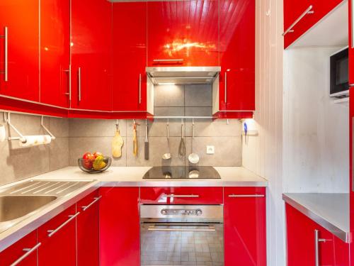 a kitchen with red cabinets and a sink at Holiday Home Le Cafetan - Les Chartreux by Interhome in Tignes