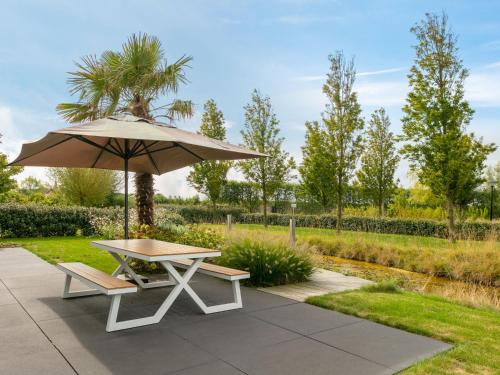 a picnic table with an umbrella and a bench at Holiday Home Ruisweg 80 by Interhome in Wemeldinge