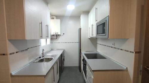 uma cozinha com armários brancos, um lavatório e um micro-ondas em Los Soportales em Soria