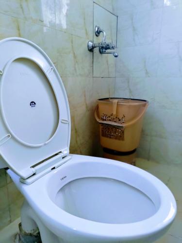 a white toilet in a bathroom with a bucket at Entire Studio Apt/Suite near Mall/Metro/ExpoMart in Noida