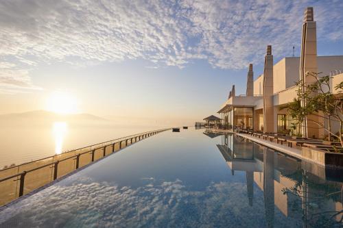 a swimming pool with the sun setting over the water at Da Nang Mikazuki Japanese Villas & Spa in Da Nang