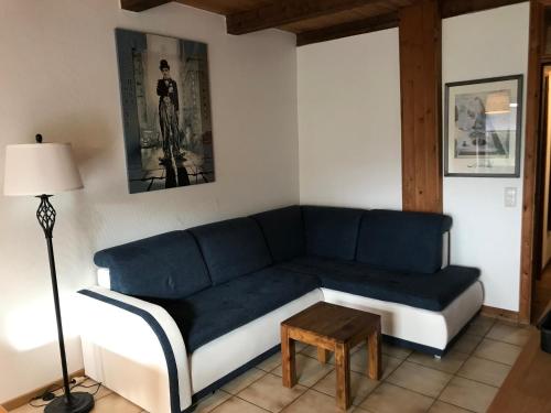 a living room with a blue couch and a table at Ferienanlage Achtern Diek in Thalingburen