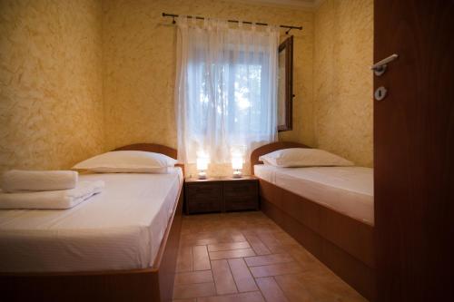 dwa łóżka w pokoju z oknem w obiekcie Apartman Mediterraneo w mieście Supetar