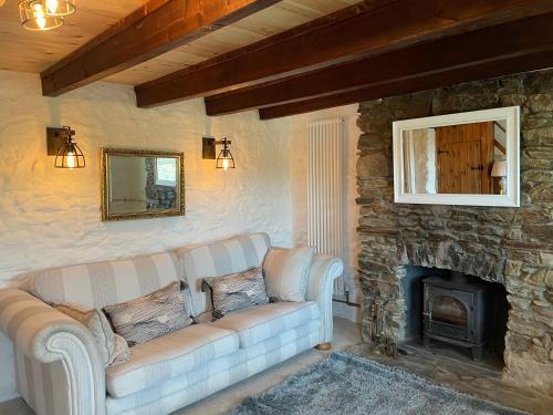 a living room with a couch and a stone fireplace at Buttercup Cottage, located in the gateway to Eden! in Saint Blazey