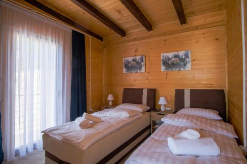 two beds in a room with wooden walls at Villa unforgettable in Sarajevo