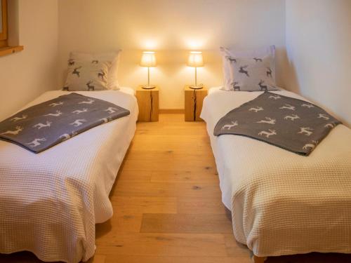 two twin beds in a room with two lamps at Apartment Chalet Sans Soucis by Interhome in Chesières