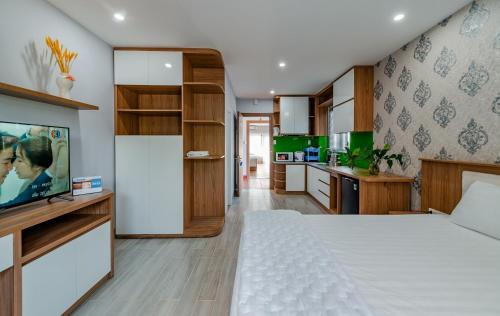 a bedroom with a white bed and a kitchen at Coco Homestay in Phu Quoc