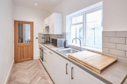 uma cozinha branca com um lavatório e uma janela em Host & Stay - High Street Apartments em Caernarfon