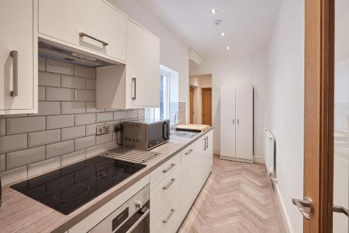 uma cozinha com armários brancos e um micro-ondas em Host & Stay - High Street Apartments em Caernarfon