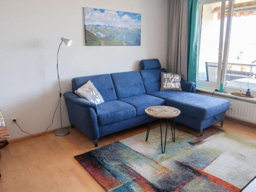 Apartment Alpensicht by Interhome في هوتشنشوند: أريكة زرقاء في غرفة المعيشة مع طاولة