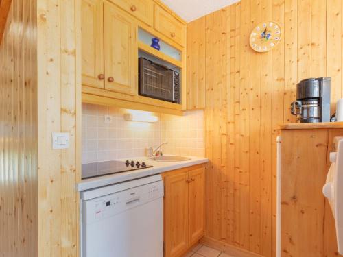 La cuisine est équipée de placards en bois, d'un évier et d'un four micro-ondes. dans l'établissement Apartment Brelin La Challe 832 by Interhome, aux Menuires