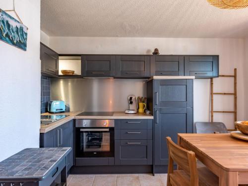 uma cozinha com armários azuis e uma mesa de madeira em Apartment Ortal Océan-9 by Interhome em Lacanau-Océan