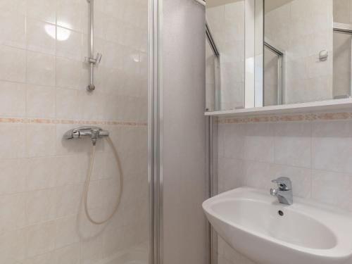 une salle de bain blanche avec une douche et un lavabo dans l'établissement Apartment Les Lauzes D25 by Interhome, aux Menuires