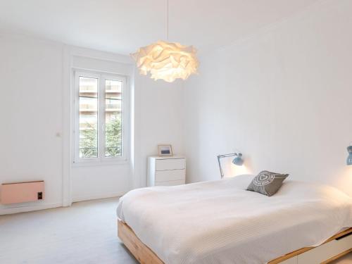 - une chambre blanche avec un lit et un lustre dans l'établissement Apartment L'écluse-2 by Interhome, à Dinard