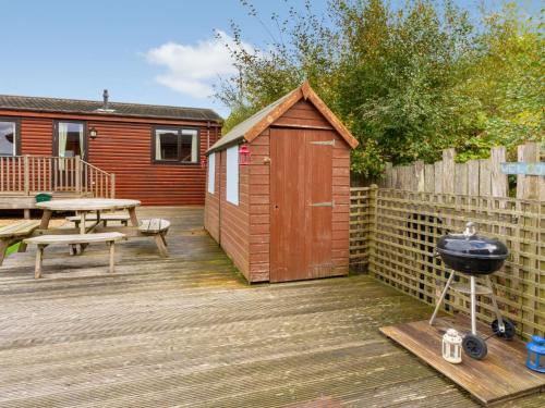 a wooden deck with a barbecue grill and a fence at Chalet Lodge 9 by Interhome in Kinross
