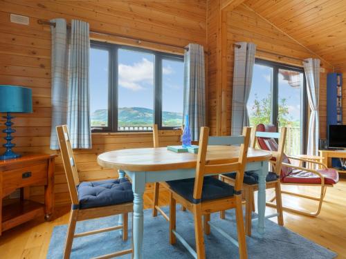 a dining room with a table and chairs and windows at Chalet Lodge 9 by Interhome in Kinross