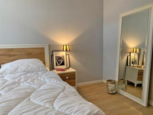 a bedroom with a large white bed and a mirror at Ferienhaus Cozy Cottage 1 in Neue Tiefe Fehmarn