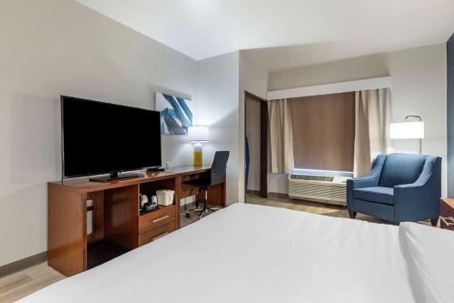 a hotel room with a bed and a television and a chair at Comfort Inn & Suites Bennett in Bennett
