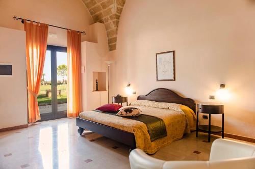 Schlafzimmer mit einem Bett, einem Tisch und einem Fenster in der Unterkunft Tenuta La Baronessa Resort in Tuglie