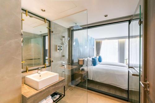 a bathroom with a bed and a sink and a mirror at Best Western Plus Nexen Pattaya in Pattaya Central