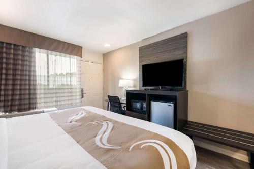 a hotel room with a bed and a flat screen tv at Quality Inn in Gastonia