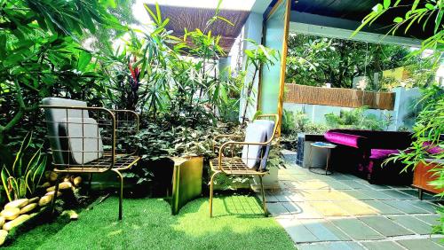 2 chaises assises dans un jardin orné de plantes dans l'établissement Giovanni House, à Bhopal