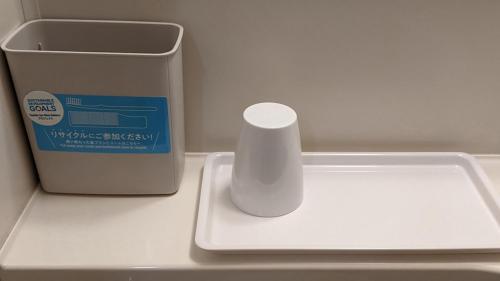 a white vase sitting next to a trash can at Toyoko Inn Matsuyama Ichibancho in Matsuyama