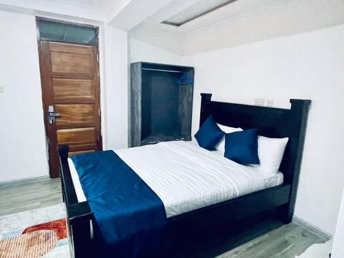 a bedroom with a blue and white bed and a door at Abby Studio Apartment with Swimming Pool in Nanyuki