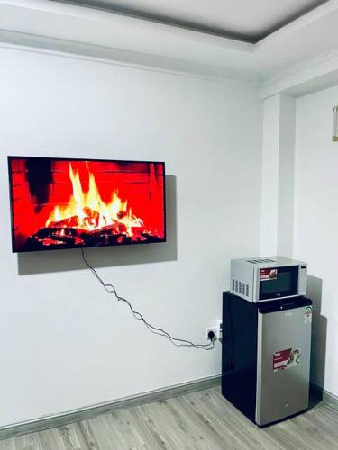 a tv on a wall with a fire on it at Abby Studio Riverside Apartment with Swimming Pool in Nanyuki