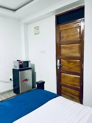 a bedroom with a bed and a wooden door at Abby Studio Riverside Apartment with Swimming Pool in Nanyuki